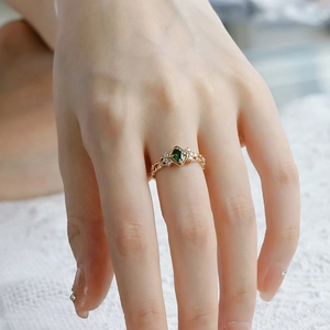 Macro view of vintage S925 silver gold ring with emerald green stone and lace detail