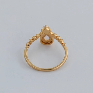 Detail view of pear-cut pink crystal ring with 14k gold plating and small pearl accent