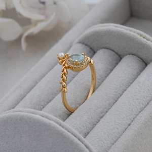 Macro detail of S925 silver gold ring with blue pear gemstone, pearl and leaf