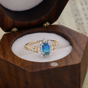 Detailaufnahme des smaragdgeschliffenen blau-grünen Quarzrings in Vintage-Holzbox