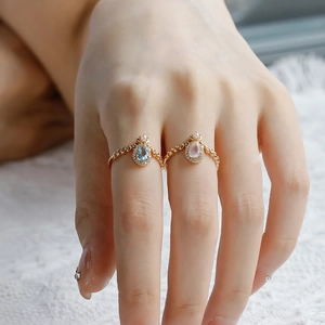 Macro detail of pear-cut blue topaz and pink quartz rings with wheat-ear texture and small pearls