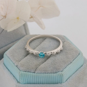 Macro detail of S925 silver rose ring with blue apatite gem on blue velvet box