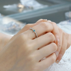 Detail of S925 silver rose thorn ring with blue apatite stone worn on lace background