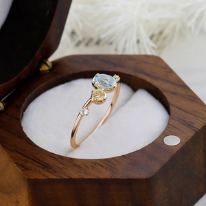 Detail of S925 silver 14K gold ring with oval blue topaz and side stones in a jewelry box