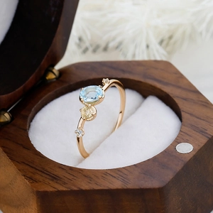 Macro shot of S925 silver 14K gold ring with sky blue topaz in a wooden gift box