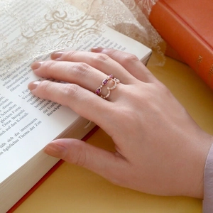 Detail von Roségoldringen mit lila Marquise-Edelstein, geschichtet auf Buchhintergrund