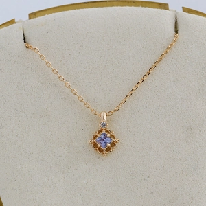 Detailed macro view of gold hollow geometric pendant with square purple tanzanite stone
