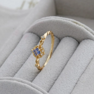 Detailed close-up of S925 silver 14K gold ring with square blue tanzanite and filigree design