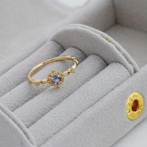 Detailed close-up of S925 silver 14K gold-plated ring with blue tanzanite in jewelry box