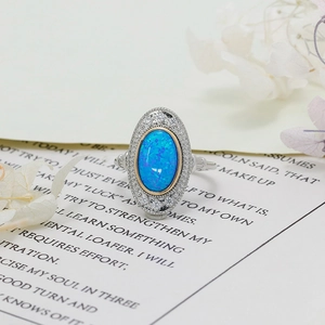 Makroaufnahme von Vintage S925 Silber Opal Ring mit blauem Feuer und Goldrand auf Buch