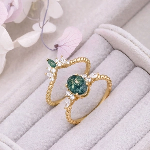 Close-up of gold moss agate ring set with marquise zircons in a grey jewelry box