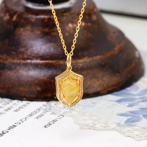Macro-opname van vintage S925 zilveren 14K gouden schildhanger met rutielkwarts edelsteen