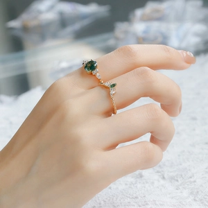 Detail of moss agate stacking rings featuring a twisted gold band and marquise zircon accents