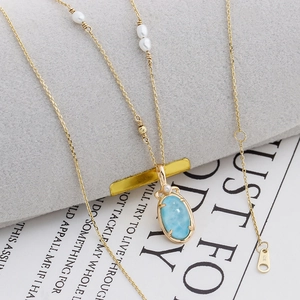 Détail du poinçon G18K sur collier en or avec pierre larimar et perles élégantes