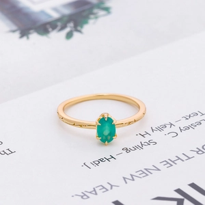 Detailed macro of a gold-finish ring with oval green gemstone and textured band