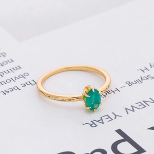 Detail of an oval green gemstone set in a vintage golden ring with engraved band