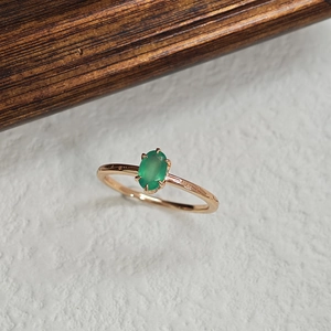 Detail of oval green chalcedony stone in rose gold four-prong setting silver ring