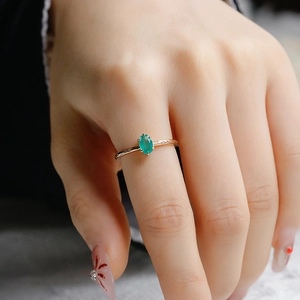 Close-up of model wearing a gold minimalist ring with oval green chalcedony gemstone
