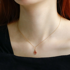 Detail of vintage S925 silver gold-plated necklace with orange garnet pendant on neck