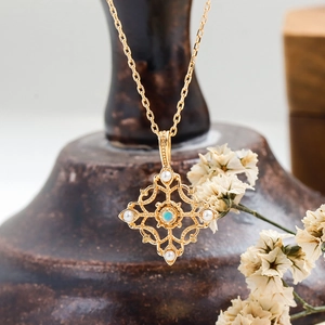 Detalle de colgante vintage bañado en oro con opalo y perlas sobre fondo cerámico