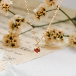 Gros plan d'un pendentif rubis rond sur une chaîne en or avec un fond vintage