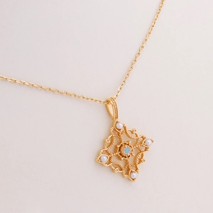 Colgante retro de oro calado con opalo y perlas blancas sobre un fondo minimalista