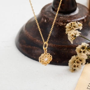 Détail d'un pendentif doré ajouré avec nacre blanche et cristaux au style rétro