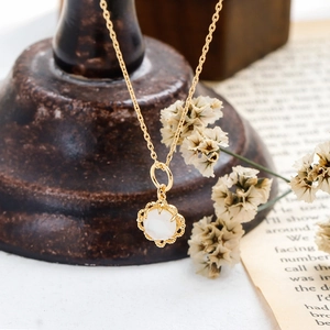 Gros plan du pendentif élégant en nacre blanche et cristal sur une fine chaîne dorée