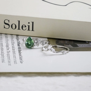 Detailopname van de ringenset met peervormige groene agaat en diamanten met rankenstructuur
