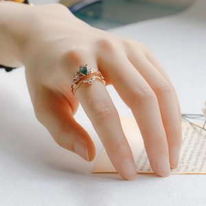 Detail van gelaagde S925 zilveren ringen met mosagaat en gouden wijnstokblad op de vinger