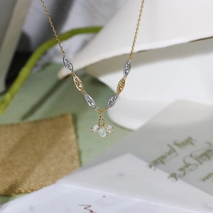 Detail view of flower-shaped pendant with three pear-cut translucent gemstones on a bicolor chain