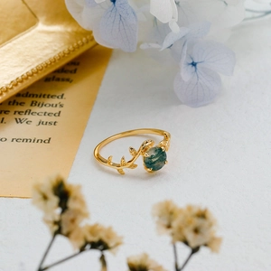 Detailed shot of a gold vine ring with natural moss agate in a vintage leaf design