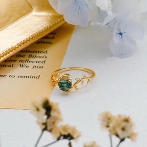 Macro shot of S925 silver gold-plated ring with green moss agate and leaf vine texture