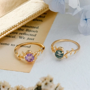Detail of amethyst and moss agate rings featuring golden vine and leaf bands