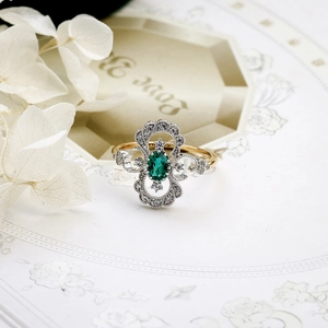 Macro d'une bague émeraude ovale avec anneau en or filigrané et zircons blancs