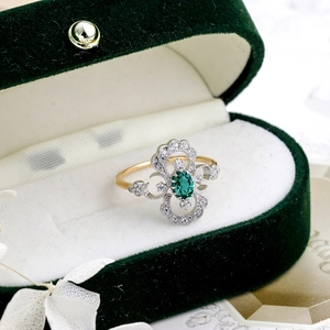 Détail d'une bague émeraude vintage avec zircons dans un écrin en velours vert
