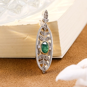 Macro shot of vintage S925 silver pendant with green chalcedony and leaf filigree