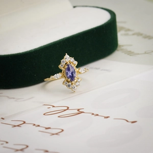 Makroaufnahme des 14K vergoldeten Rings mit lila Zirkonia auf grünem Samtkissen