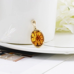Détail d'un pendentif en ambre avec cadre doré ciselé suspendu à une tasse en porcelaine