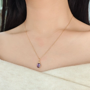 Dettaglio di una collana con pendente in ametista a doppia faccia su modella dorata
