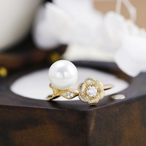 Macro detail of a 3D lotus pearl ring with moissanite accents and golden floral design