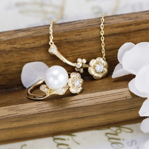 Detail view of a luxury pearl ring and necklace set with lotus flower motifs and diamonds