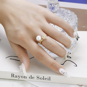 Detailed shot of elegant gold lotus ring with white pearl and rhinestone on a hand
