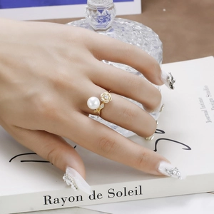 Close-up of luxury gold lotus ring with pearl and moissanite stones on finger