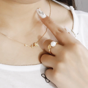 Close-up of a gold lotus necklace and a pearl flower ring set worn by a female model