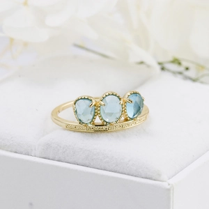 Detail of s925 gold plated ring with blue rose-cut stones in a white velvet box