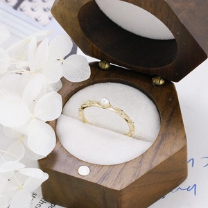 Detailed macro view of a vintage gold pearl ring in a premium hexagonal walnut wood gift box