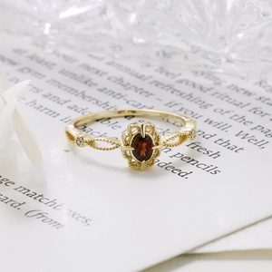 Macro detail of garnet ring featuring vintage lace gold plating and small side diamonds