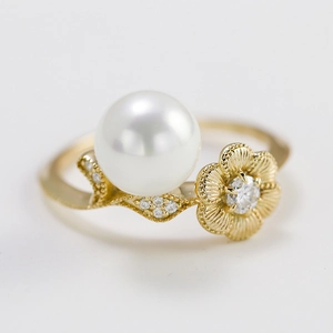 Elegant gold lotus ring featuring a white pearl and shimmering moissanite on white background