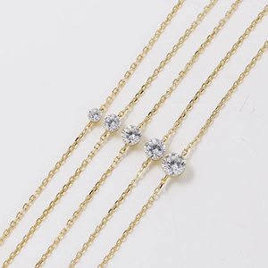 Detailed macro view of five gold-plated necklaces with bezel-set round sparkling zircons